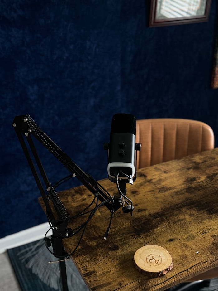 about-01 A dynamic microphone setup for podcasting on a rustic wooden table in a recording studio.